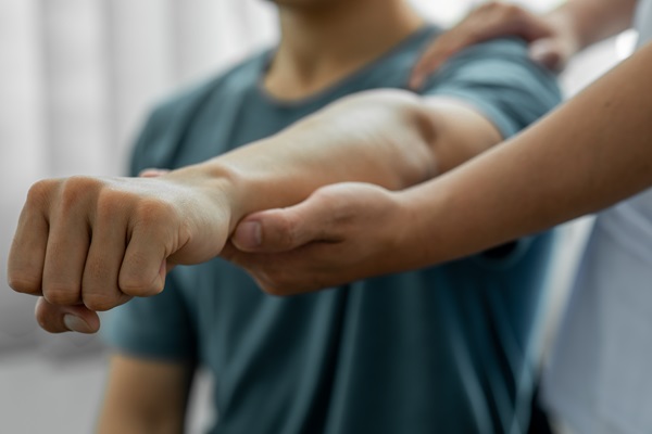 Injured person undergoing a physical evaluation, with a medical professional assisting arm movement during an independent medical exam.